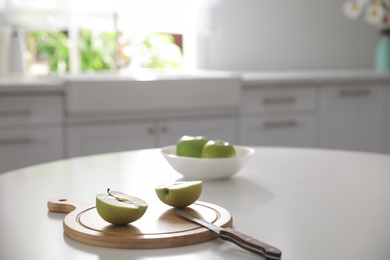 Photo of Halves of fresh apple and knife on white table in kitchen. Space for text