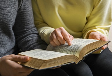 Photo of Couple sitting and reading holy Bible, closeup