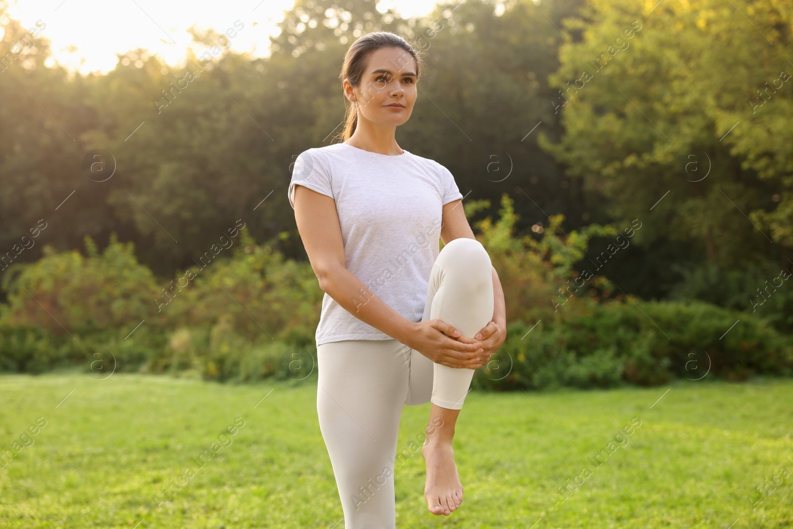 Photo of Beautiful young woman practicing yoga in park outdoors