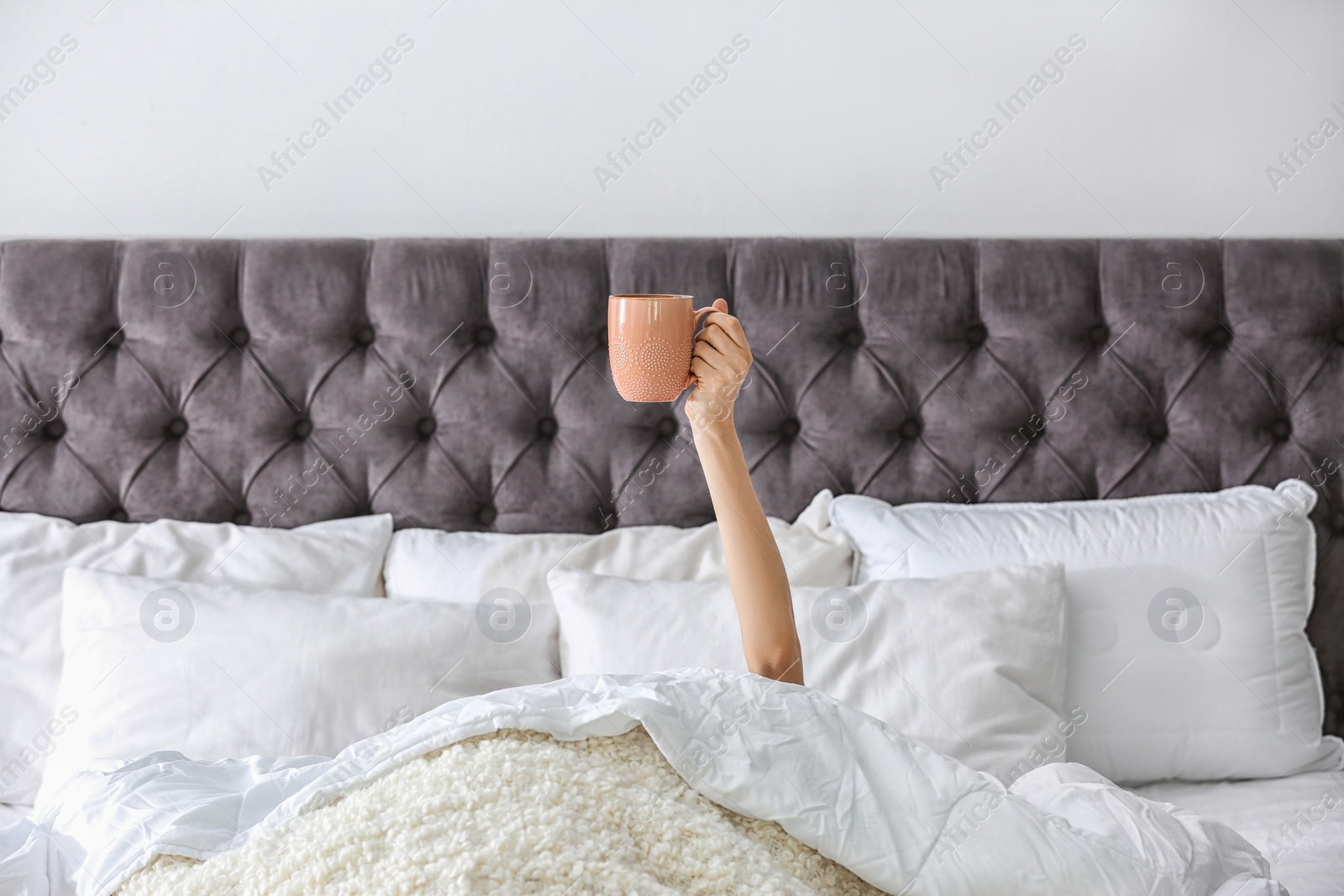 Photo of Woman with cup of coffee on bed at home