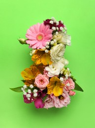 Photo of Number 8 made of beautiful flowers on green background, flat lay. International Women's day