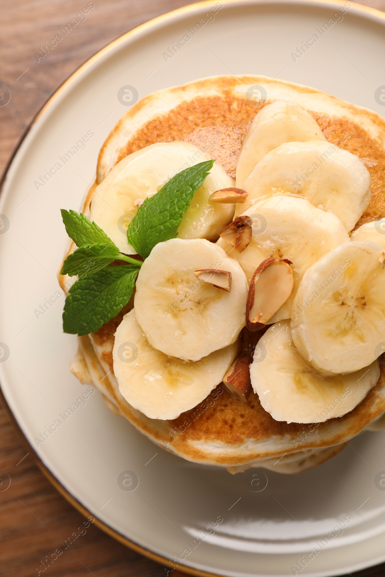 Photo of Tasty pancakes with sliced banana on wooden table, closeup