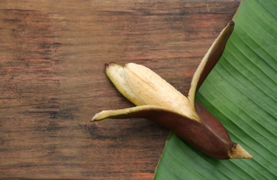 Photo of Delicious purple banana and fresh leaf on wooden table, top view. Space for text