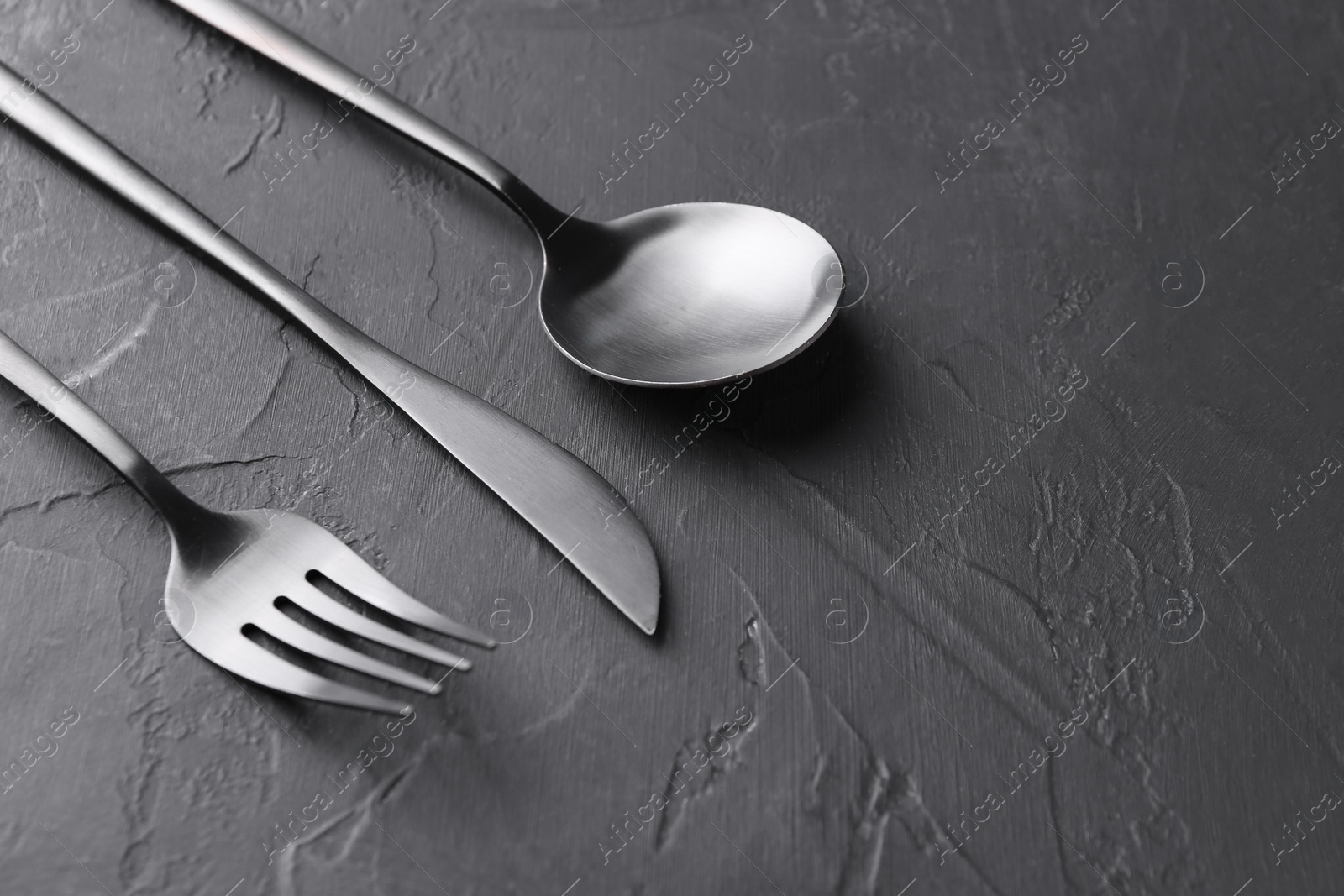 Photo of Beautiful cutlery set on black table, closeup. Space for text