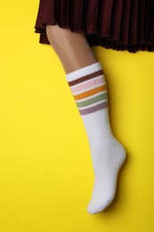 Photo of Woman wearing color sock on yellow background, closeup