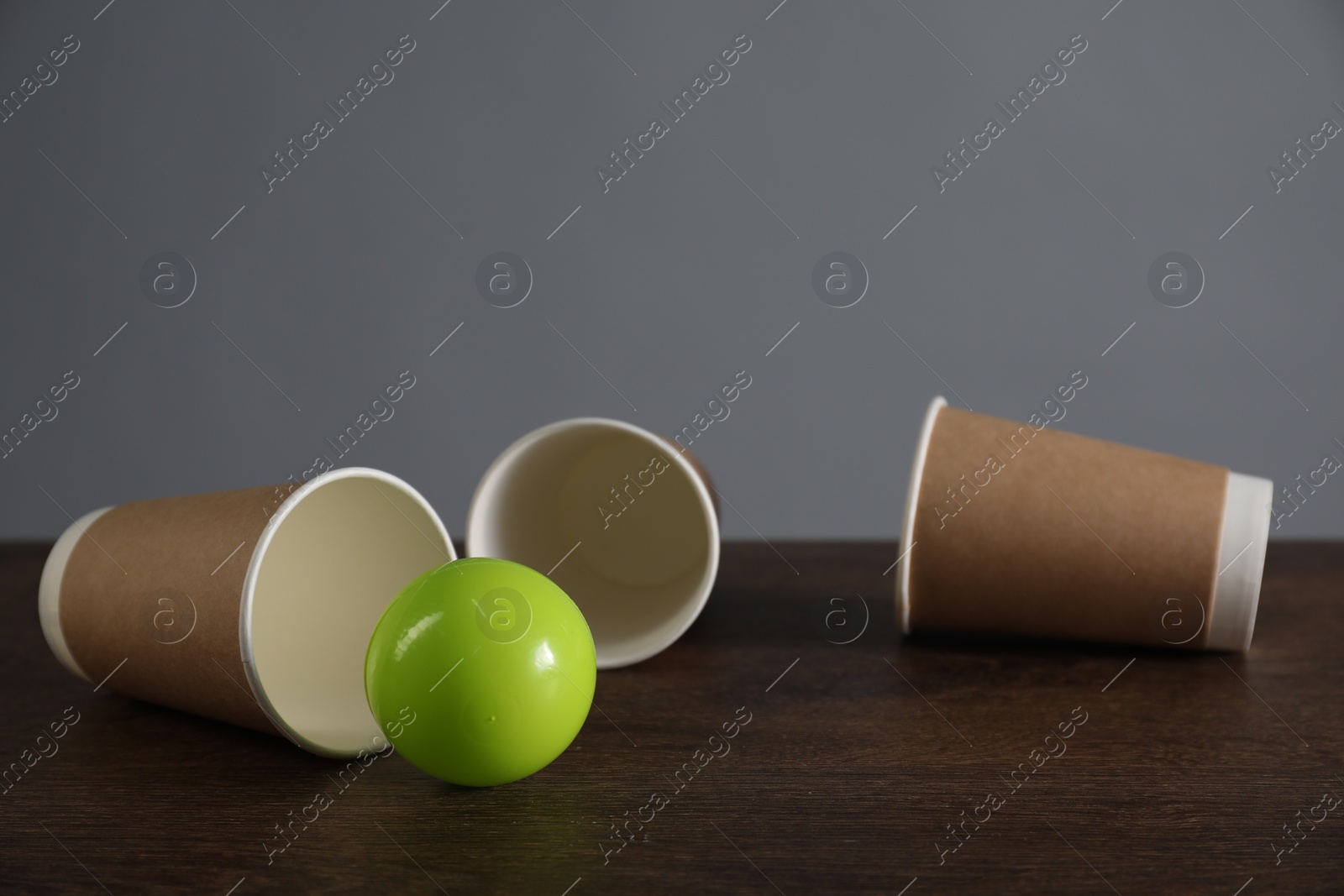 Photo of Shell game. Three paper cups and ball on wooden table