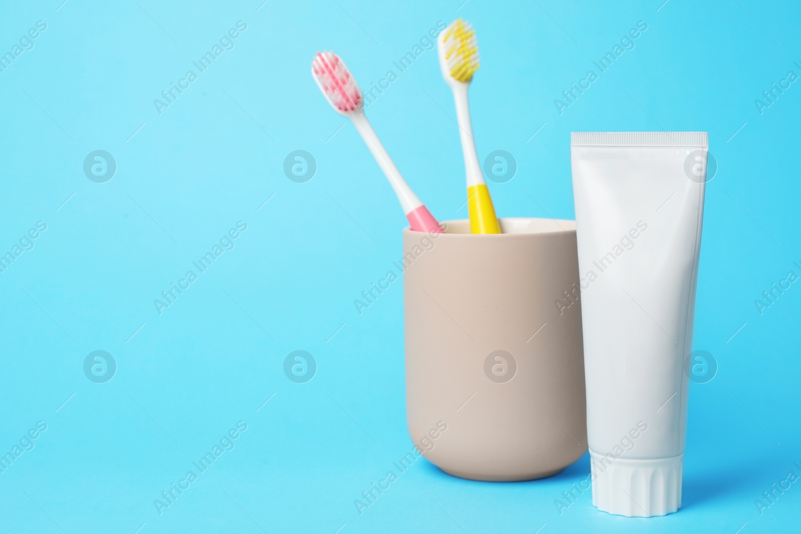 Photo of Holder with brushes and toothpaste on color background. Space for text