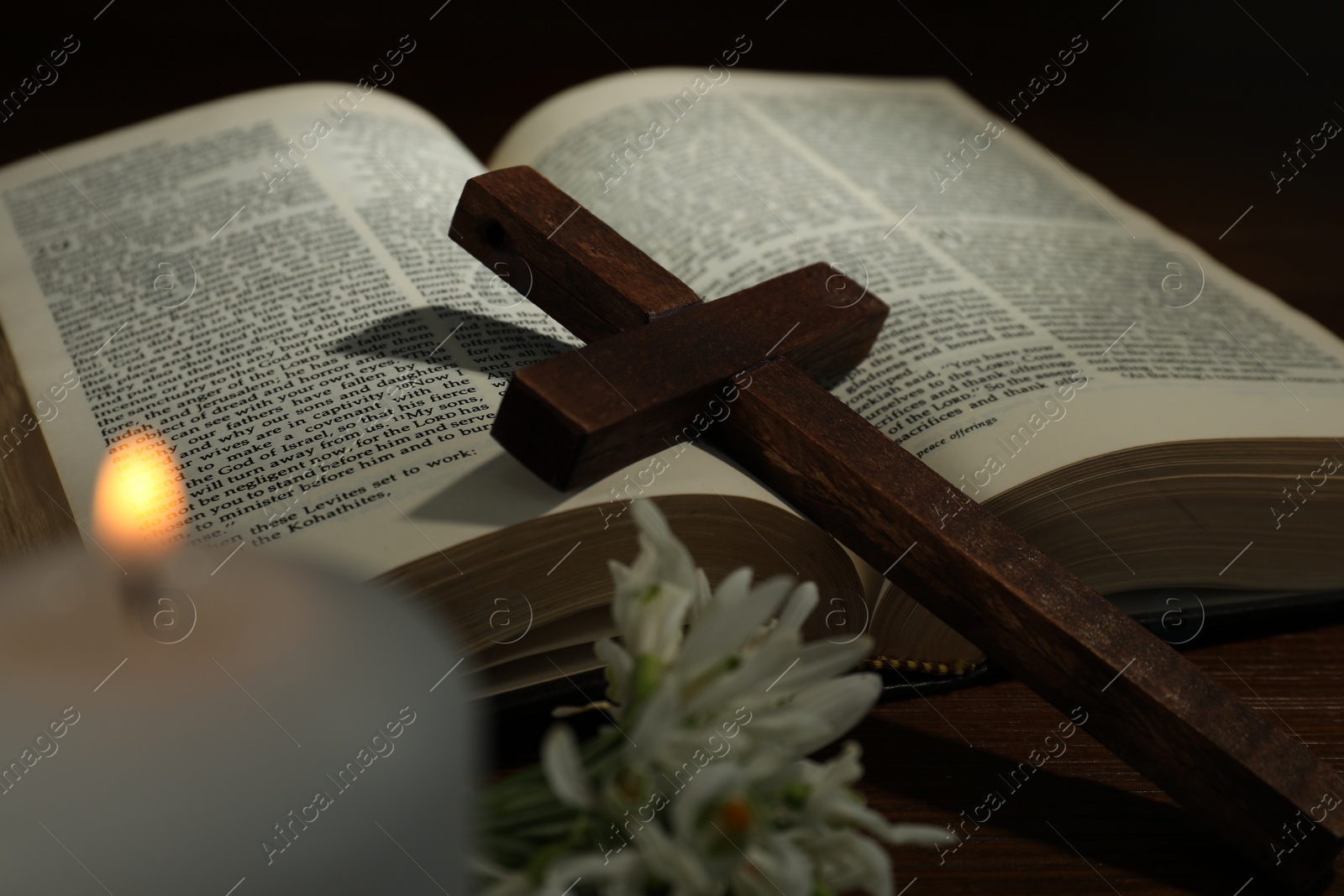 Photo of Cross, Bible, flowers and church candle on wooden table