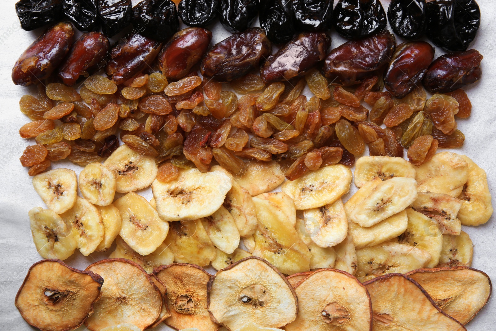 Photo of Different tasty dried fruits on paper, flat lay