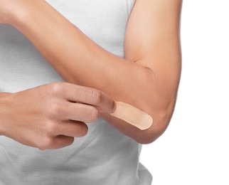 Man putting sticking plaster onto elbow on white background, closeup