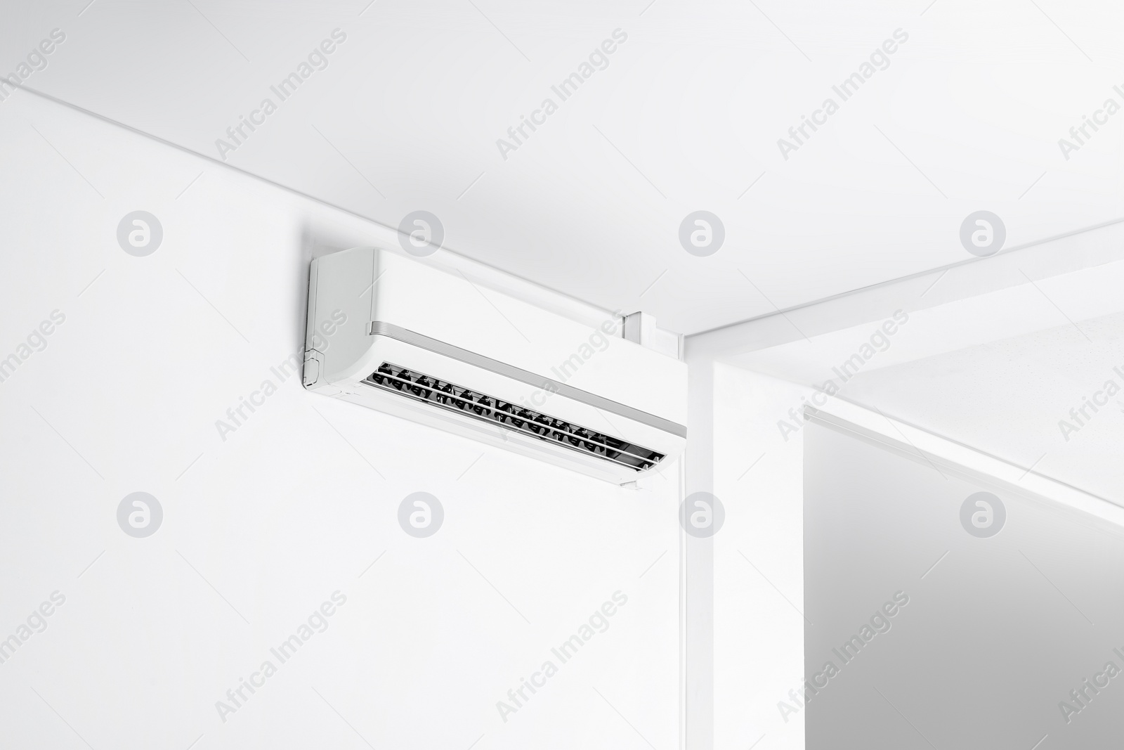 Photo of Modern air conditioner on white wall indoors. Space for text