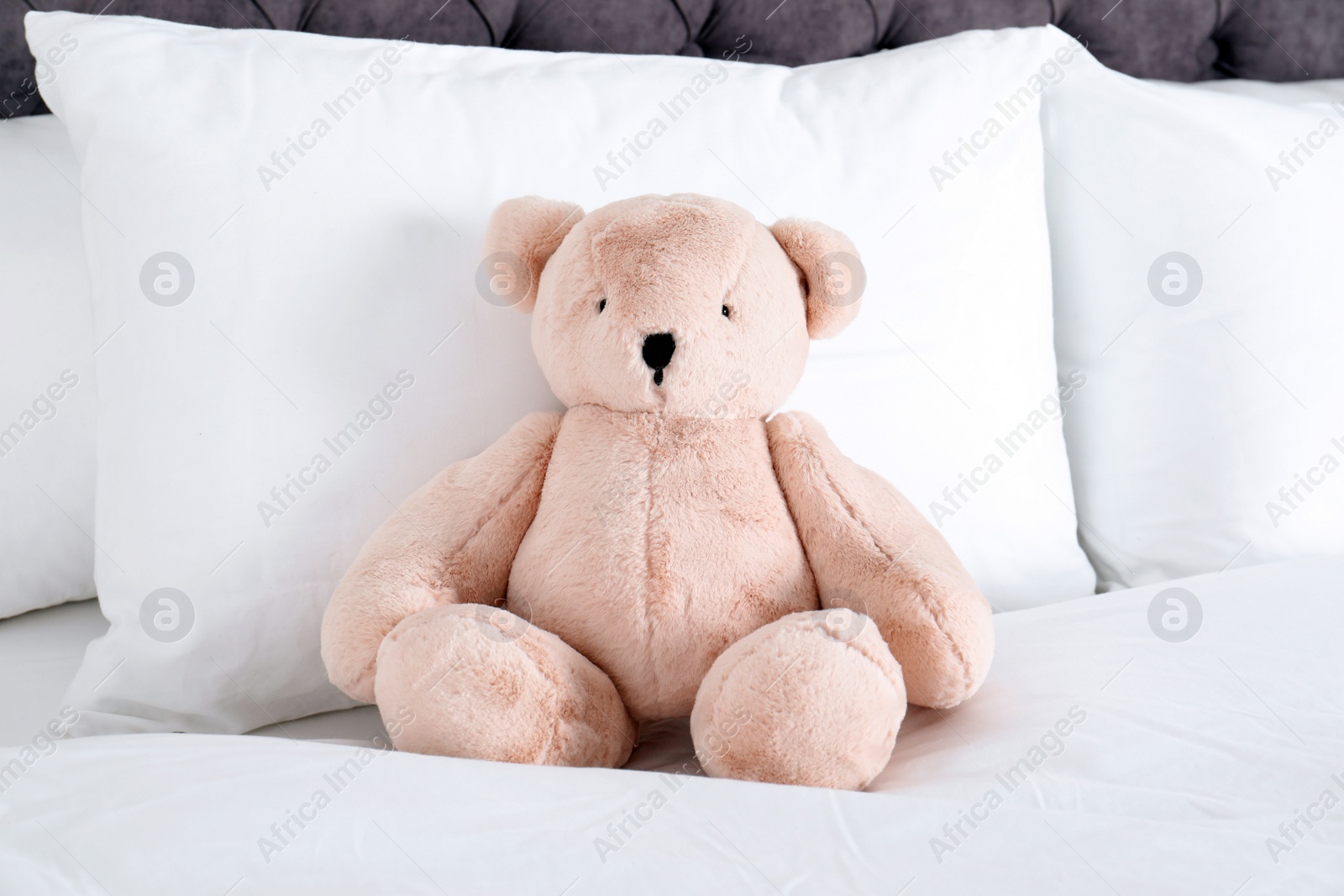 Photo of Cute teddy bear sitting on bed indoors