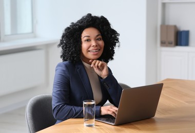 Photo of Young woman working on laptop at table in office