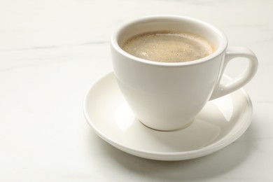 Photo of Cup of aromatic coffee on white table, closeup. Space for text