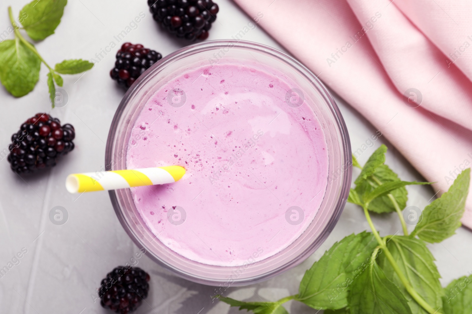 Photo of Delicious blackberry smoothie in glass and berries on white table, flat lay