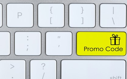Image of Yellow button with phrase Promo Code and image of gift box on computer keyboard, top view