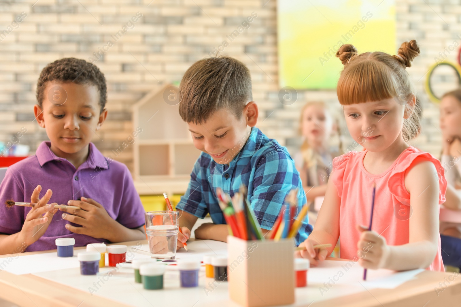 Photo of Cute little children painting at table indoors. Learning by playing