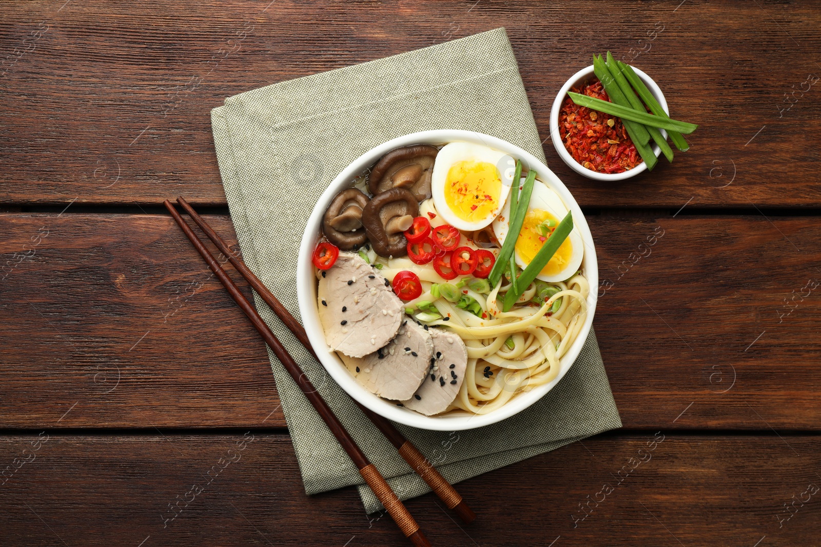 Photo of Delicious ramen with meat in bowl served on wooden table, flat lay. Noodle soup