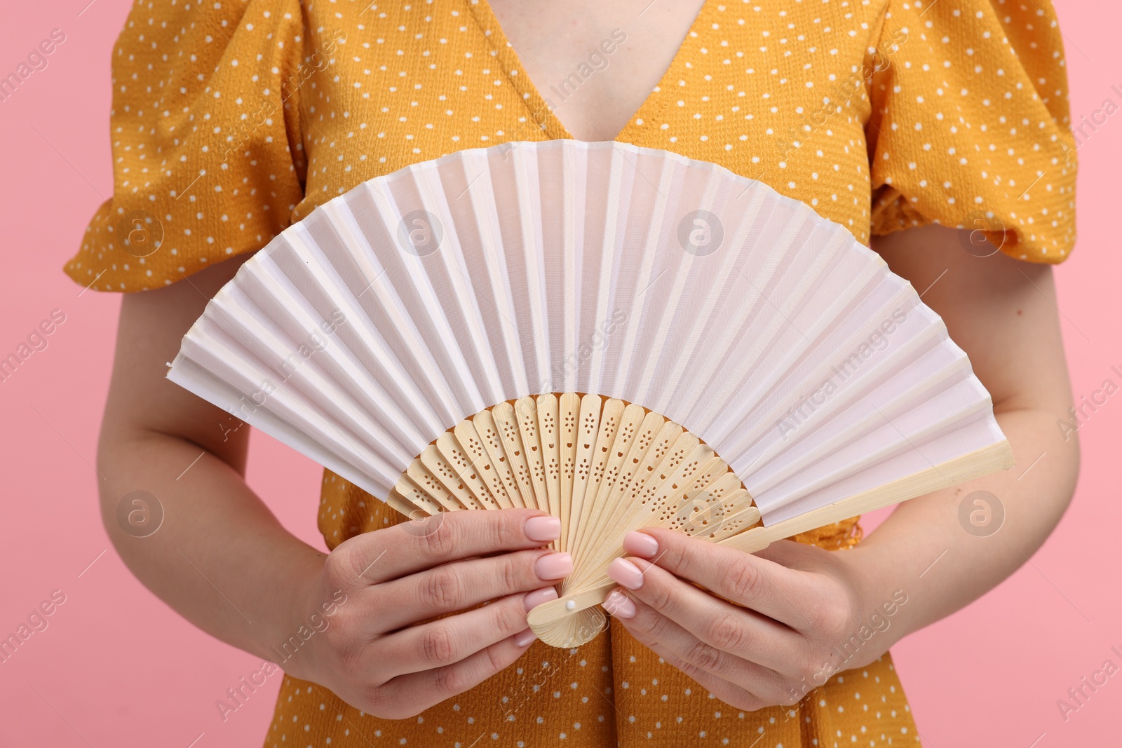 Photo of Woman with hand fan on pink background, closeup