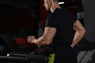Man working out on treadmill in modern gym, closeup
