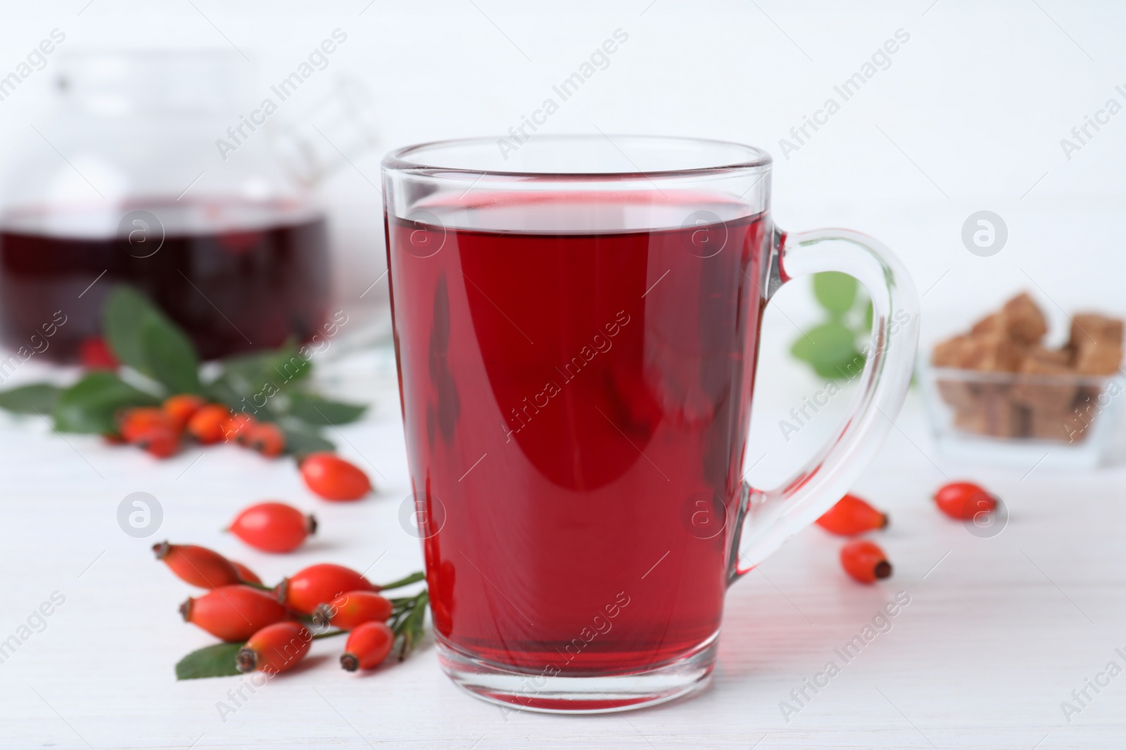 Photo of Aromatic rose hip tea and fresh berries on white wooden table, closeup