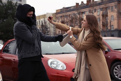 Photo of Woman using pepper spray while thief trying to steal her bag on city street. Self defense concept