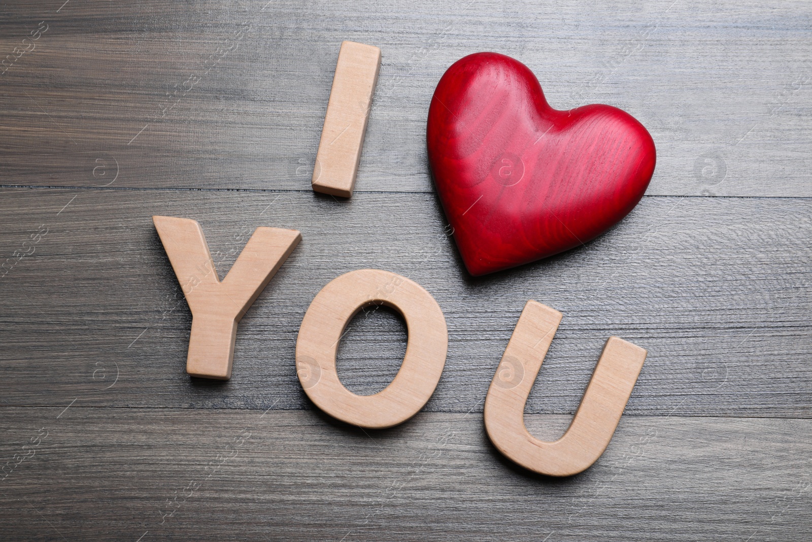 Photo of Phrase I Love You made of decorative heart and letters on wooden background, above view
