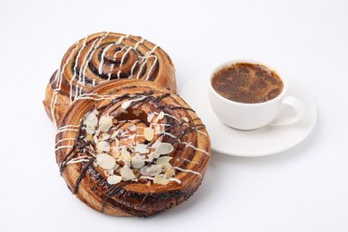 Photo of Delicious rolls with toppings, almond and cup of coffee isolated on white. Sweet buns