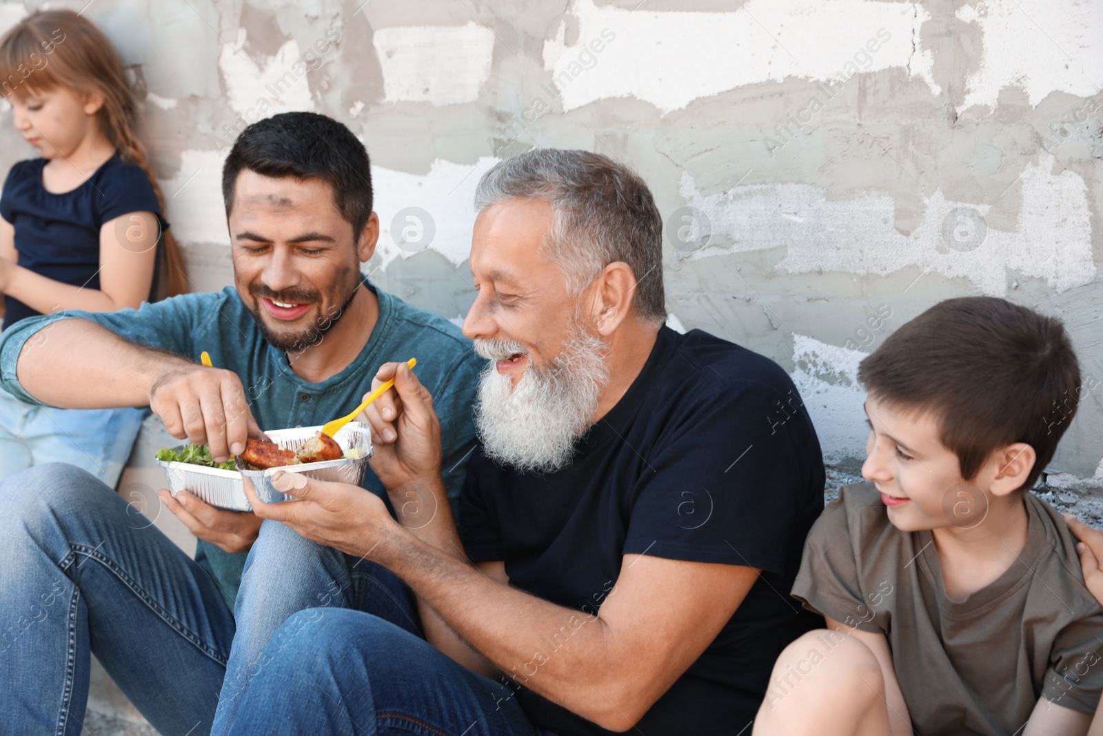 Photo of Poor people holding plates with food near wall outdoors