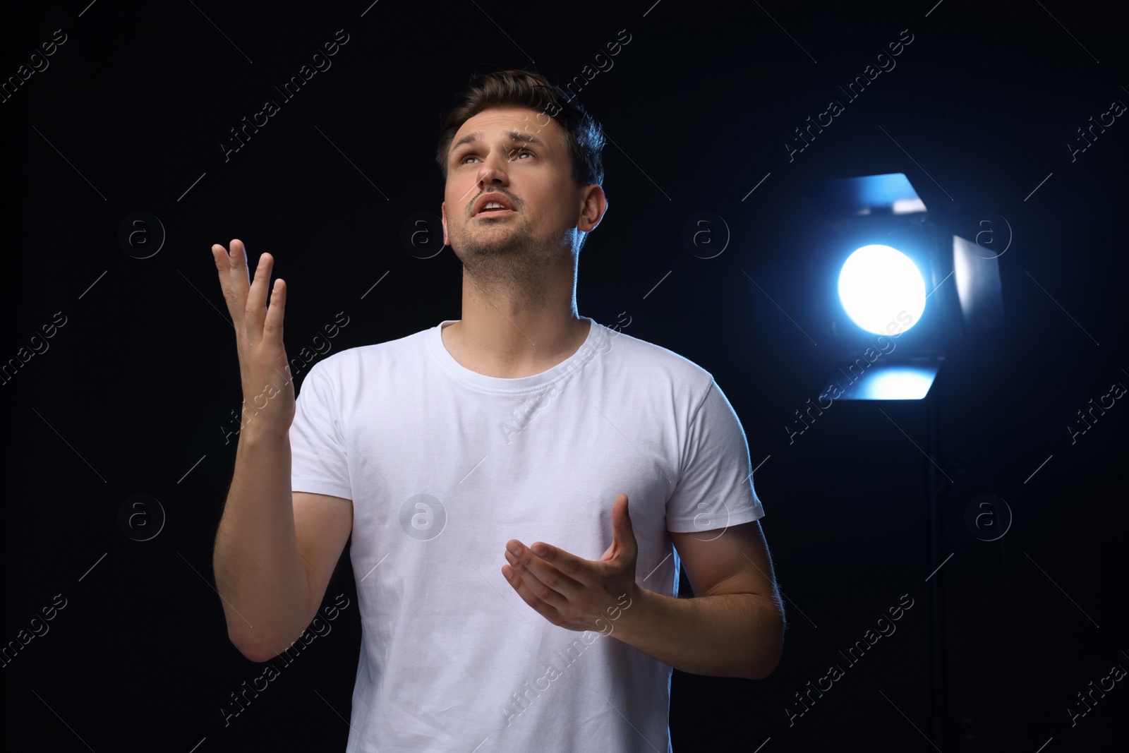 Photo of Casting call. Emotional man performing on black background