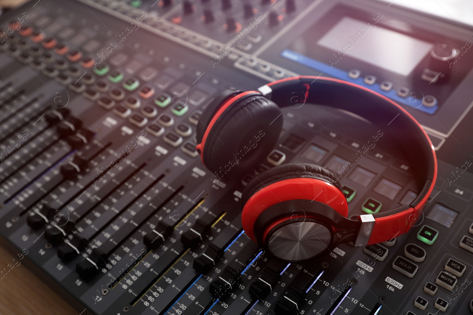 Photo of Headphones on professional mixing console in modern radio studio