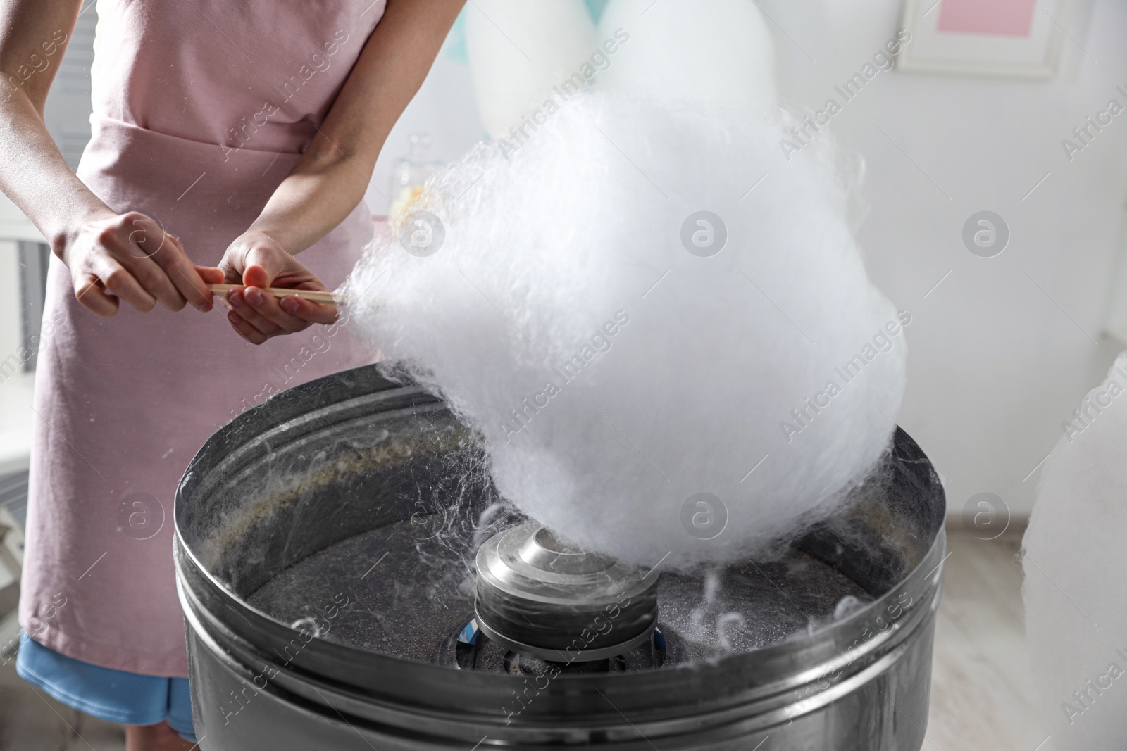 Photo of Woman making cotton candy using modern machine indoors, closeup