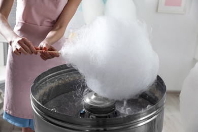 Woman making cotton candy using modern machine indoors, closeup