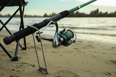 Fishing rod with reel at riverside, closeup. Space for text