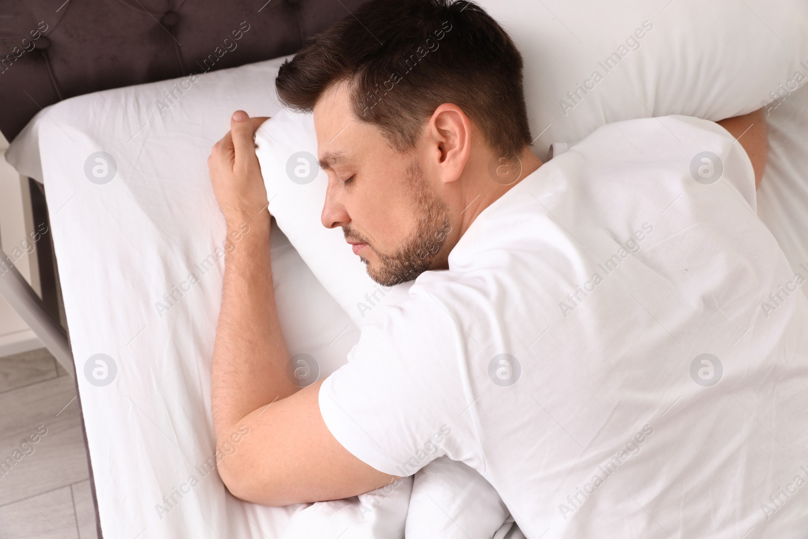 Photo of Handsome man sleeping on pillow at home, view from above. Bedtime