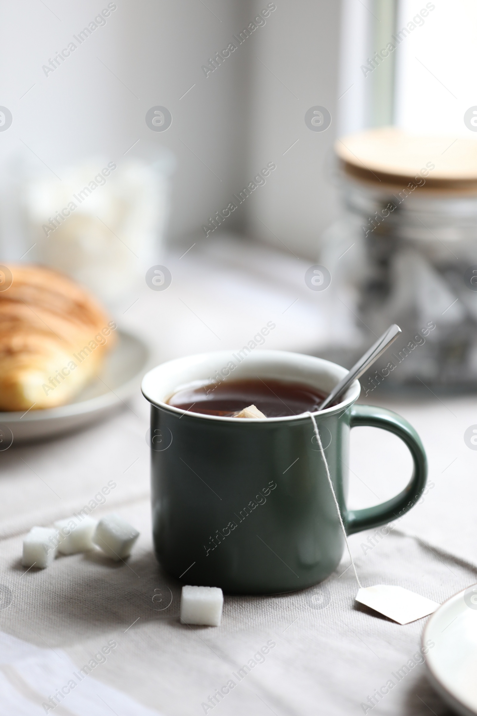 Photo of Cup of freshly brewed tea and sugar cubes on table