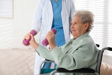 Photo of Senior woman in wheelchair doing physical exercise indoors. Home health care service