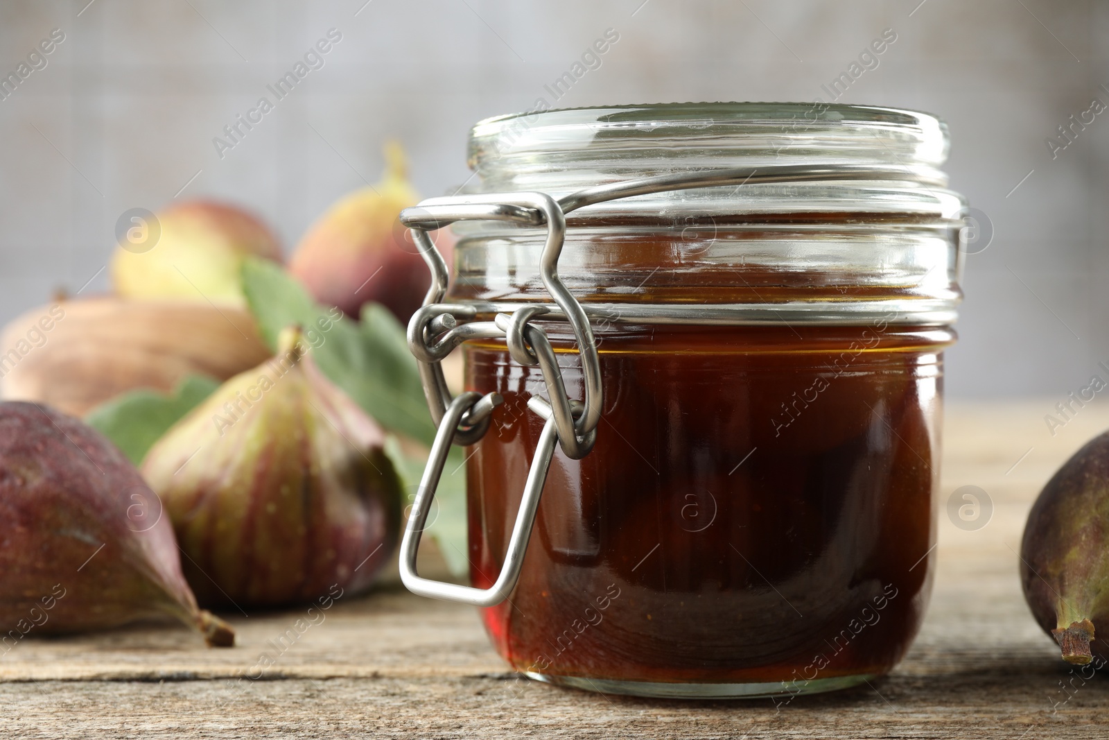 Photo of Jar of tasty sweet jam and fresh figs on wooden table