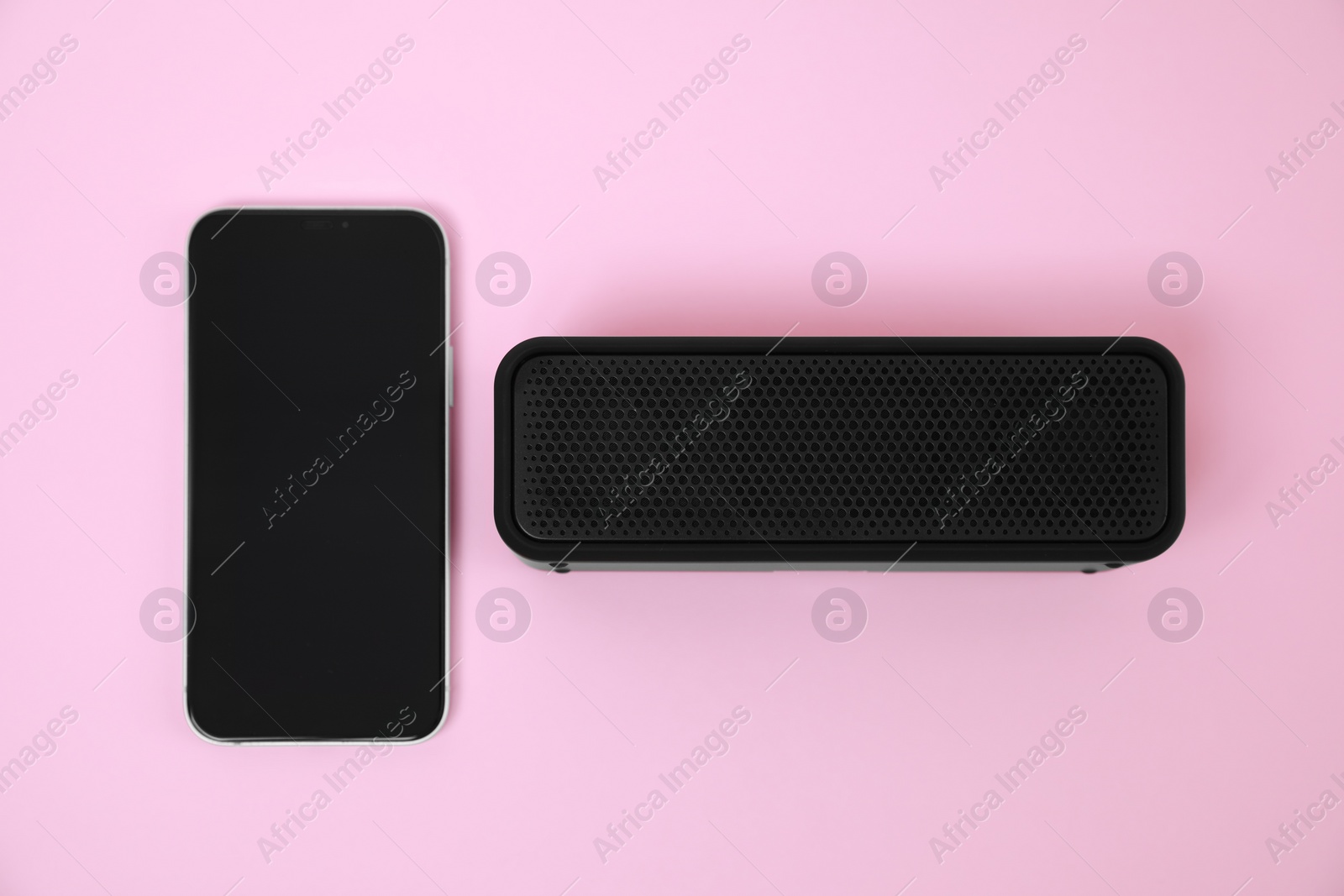 Photo of Portable bluetooth speaker and smartphone on pink background, flat lay. Audio equipment