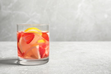 Photo of Tasty refreshing drink with strawberries and lemon on light grey table. Space for text