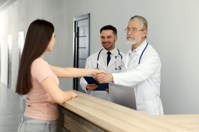 Photo of Senior doctor shaking hands with patient in hospital hall