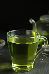 Photo of Cup of aromatic green tea on grey table