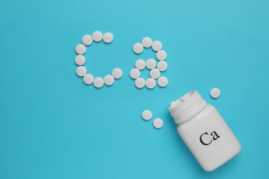 Photo of Flat lay composition with calcium supplement pills on light blue background, space for text