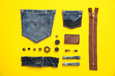 Photo of Flat lay composition with garment accessories and cutting details for jeans on yellow background