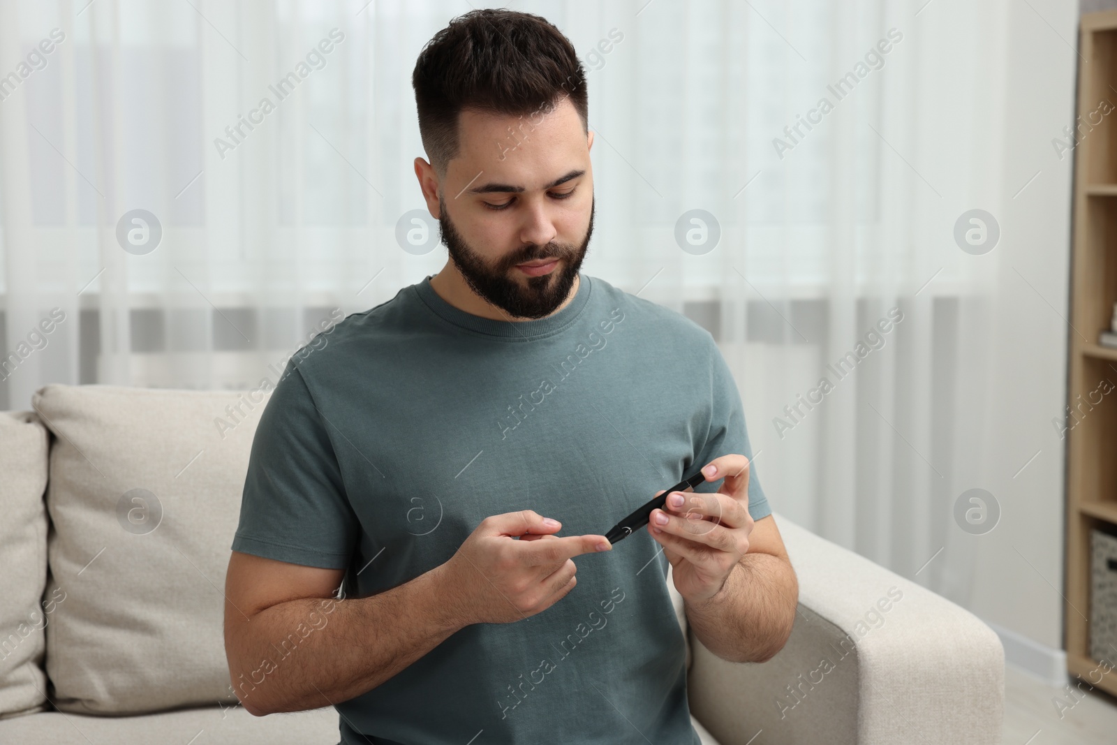 Photo of Diabetes test. Man checking blood sugar level with lancet pen at home