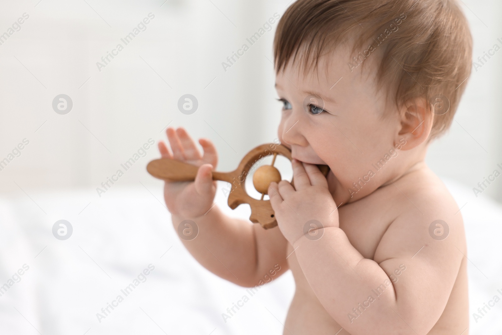 Photo of Cute baby boy with wooden rattle at home