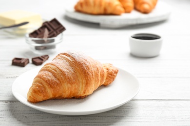 Photo of Plate with tasty croissant on white wooden table. French pastry