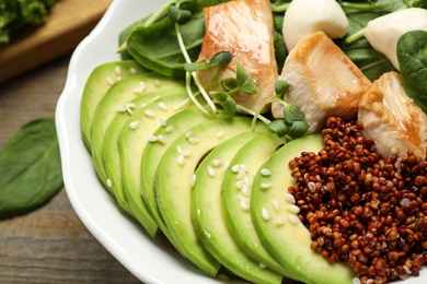 Delicious avocado salad with chicken on wooden table, closeup