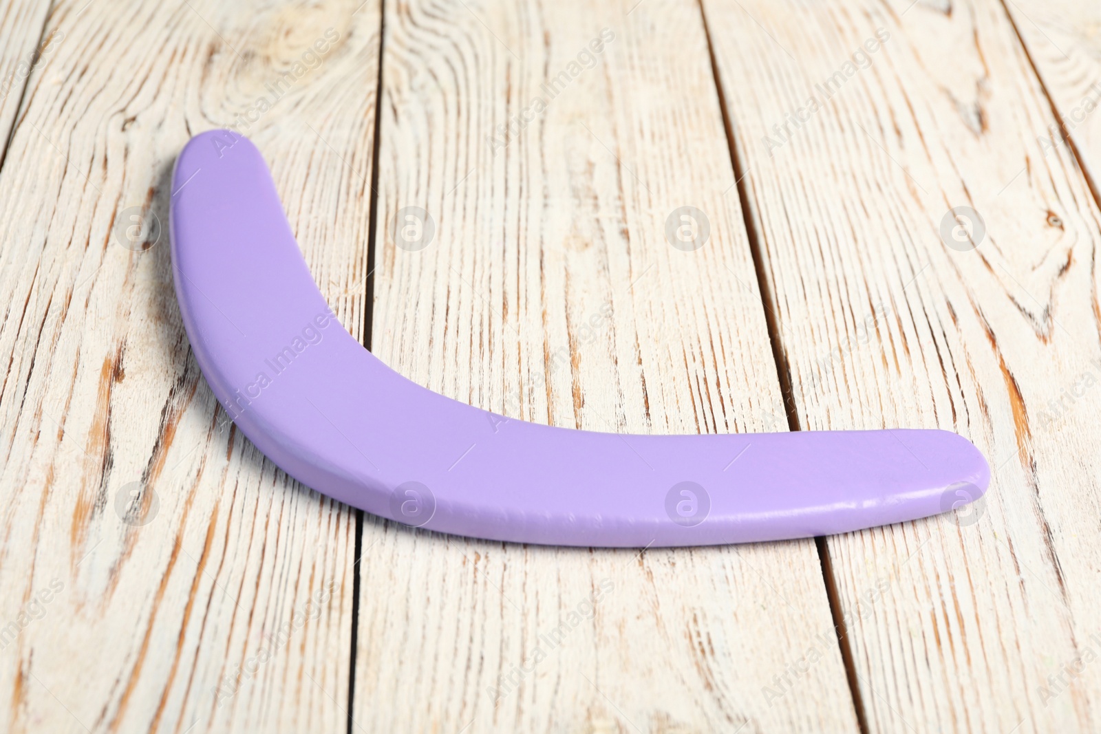 Photo of Purple boomerang on white wooden background. Outdoors activity