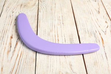 Photo of Purple boomerang on white wooden background. Outdoors activity